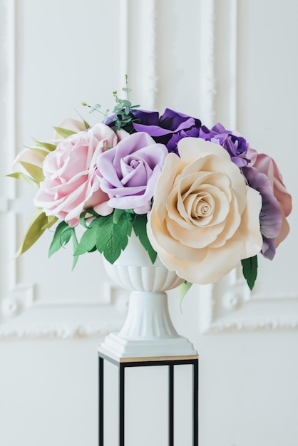 Bellissimo arredamento per il matrimonio. Composizione di fiori e vegetazione nella sala banchetti, vaso alto bianco, su sfondo bianco. Mazzo di fiori di lusso