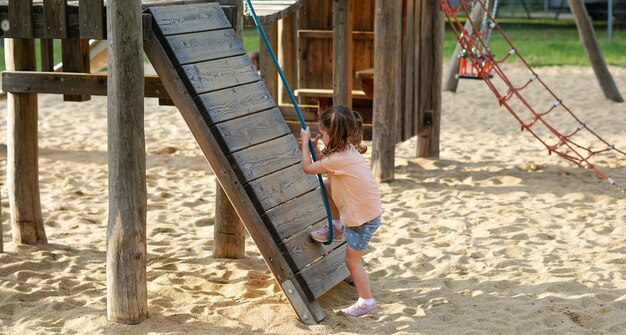 Bellissimo bambino che si diverte in una calda giornata estiva soleggiata Ragazza carina per bambini che gioca nella sabbia nel parco giochi all'aperto