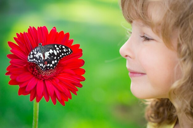 Bellissimo bambino con farfalla nel parco di primavera Bambino felice che gioca all'aperto