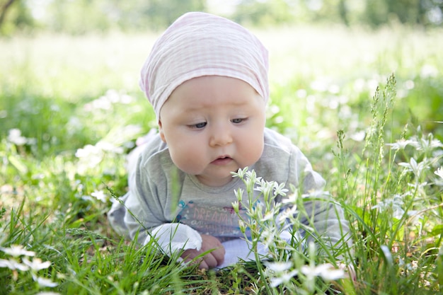 Bellissimo bambino sorpreso in un velo sdraiato sull'erba nel parco estivo