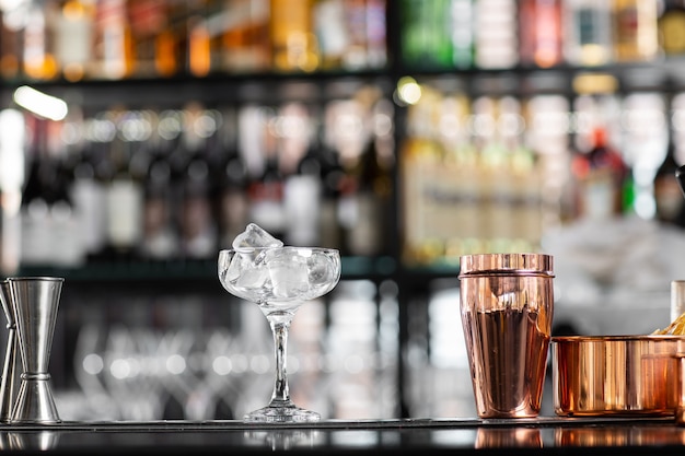 Bellissimo bicchiere trasparente con ghiaccio e portabicchieri in acciaio sul bancone del bar sullo sfondo