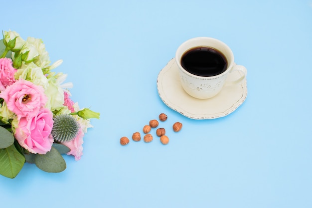 Bellissimo bouquet colorato di diversi fiori freschi e tazza di caffè nero con noci sullo sfondo azzurro