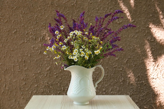 Bellissimo bouquet con fiori di campo in brocca su tavolo di legno bianco