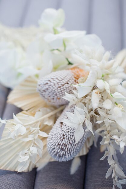 Bellissimo bouquet da sposa boho con orchidee banksia e fiori secchi su sfondo grigio