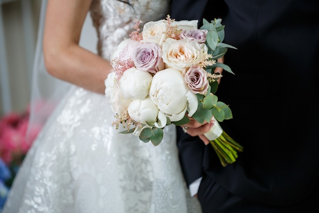 Bellissimo bouquet da sposa di fiori nelle mani degli sposi