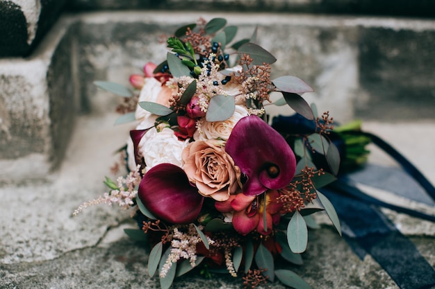 Bellissimo bouquet da sposa rosso della sposa in stile rustico su uno sfondo di pietrax9