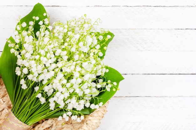 Bellissimo bouquet di fiori di mughetto in un cesto su un legno bianco