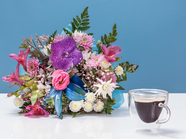 Bellissimo bouquet di fiori diversi con una tazza di caffè.