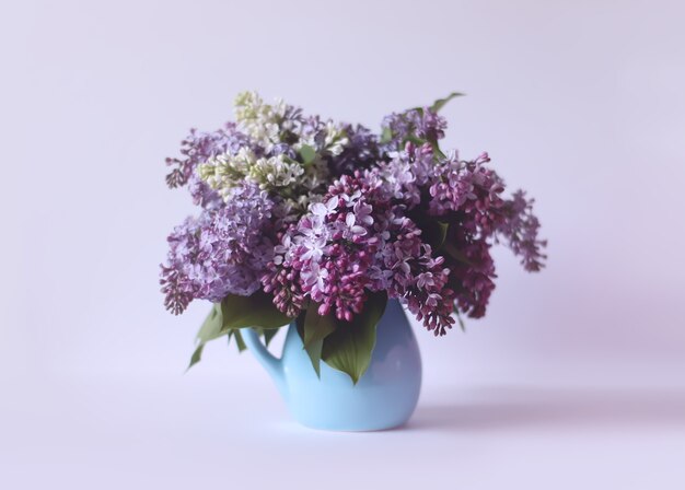 Bellissimo bouquet di fiori viola profumati in vaso di ceramica blu su sfondo chiaro. Syringa vulgaris o pianta di lillà.