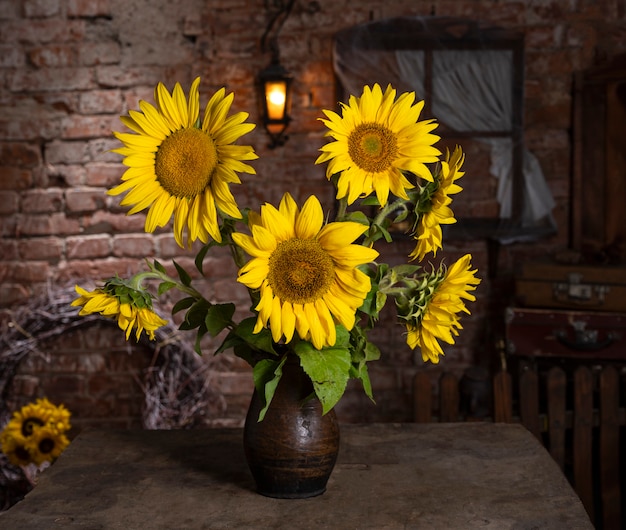 Bellissimo bouquet di girasoli in vaso su un tavolo di legno. Natura morta autunnale