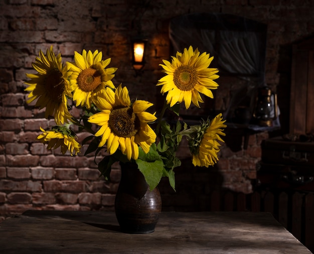 Bellissimo bouquet di girasoli in vaso su un tavolo di legno. Natura morta autunnale