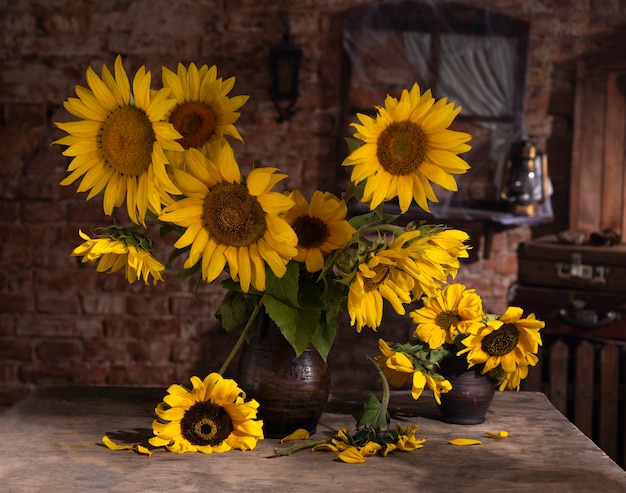 Bellissimo bouquet di girasoli in vaso su un tavolo di legno. Natura morta autunnale