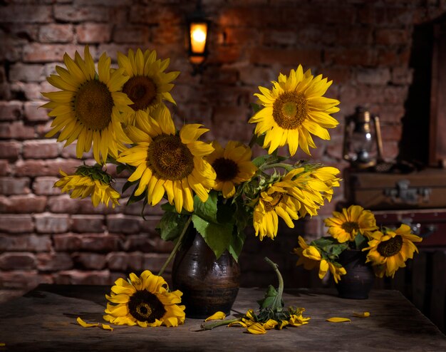 Bellissimo bouquet di girasoli in vaso su un tavolo di legno. Natura morta autunnale