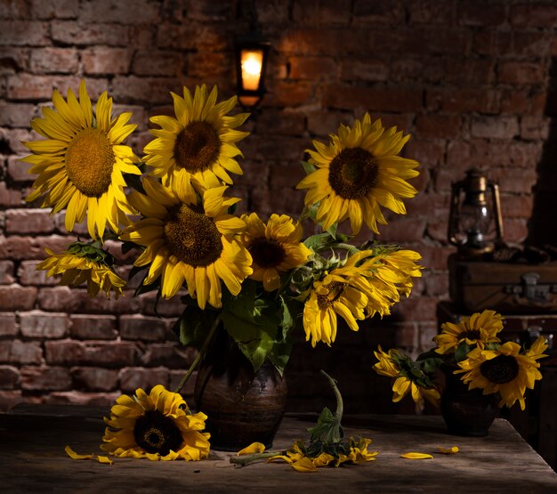 Bellissimo bouquet di girasoli in vaso su un tavolo di legno. Natura morta autunnale