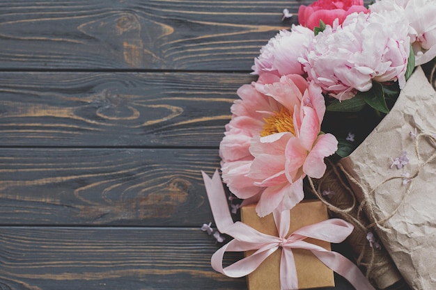 Bellissimo bouquet di peonia in carta e confezione regalo su legno scuro rustico vista dall'alto spazio copia Festa della mamma