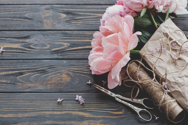 Bellissimo bouquet di peonie alla moda in spago di carta e forbici su spazio di copia in legno scuro rustico