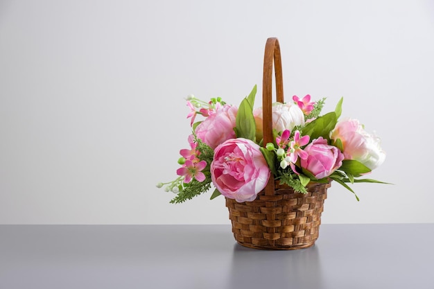 Bellissimo bouquet di peonie rosa composizione floreale in cesto di paglia su sfondo grigio chiaro