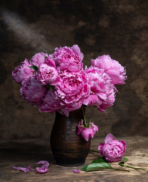 Bellissimo bouquet di peonie rosa in vaso su un tavolo di legno