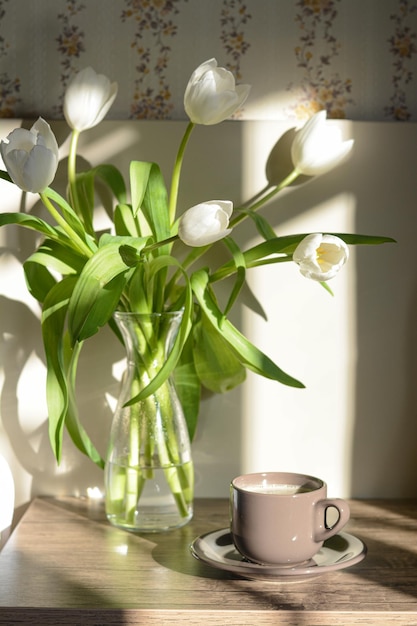 Bellissimo bouquet di tulipani bianchi e tazza di caffè sul tavolo di legno all'interno