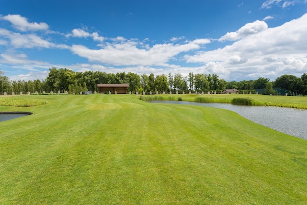 Bellissimo campo da golf con erba verde perfetta e ostacoli d'acqua in una luminosa giornata di sole