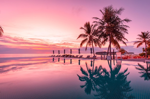 Bellissimo cielo a bordo piscina e al tramonto con palme. Nuoto a sfioro del paesaggio di spiaggia tropicale di lusso