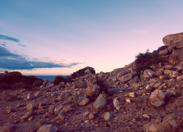 Bellissimo cielo al tramonto rosa blu scuro drammatico con nuvole sul mare e montagne di pietra rocciosa