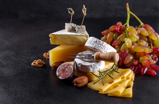 Bellissimo delizioso formaggio camembert, parmigiano, brie con uva e fichi su una tavola di legno. Spuntini per vino in vacanza