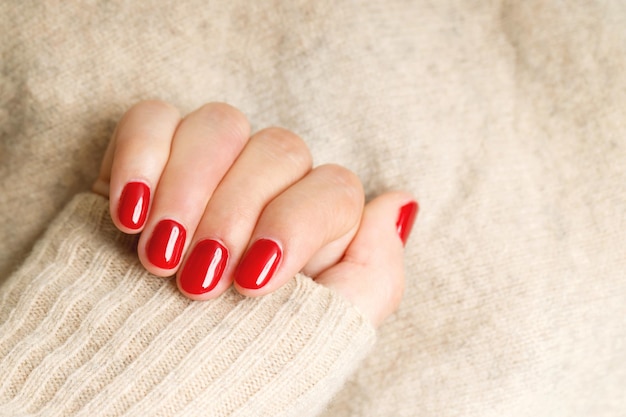 Bellissimo dipinto a mano femminile con unghie rosse in gel acrilico. Stile alla moda