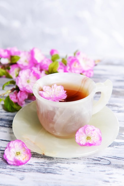 Bellissimo fiore di frutta con una tazza di tè sul tavolo su sfondo grigio