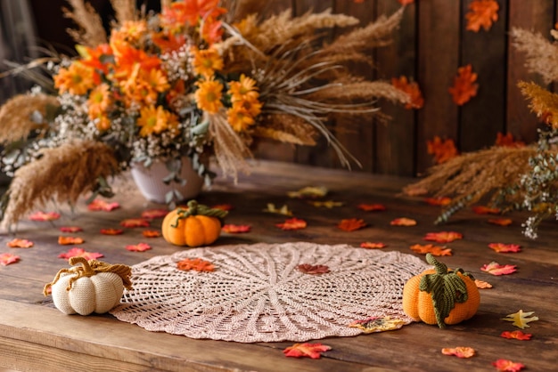 Bellissimo fotozone autunnale con foglie colorate, fiori secchi e zucche lavorate a maglia