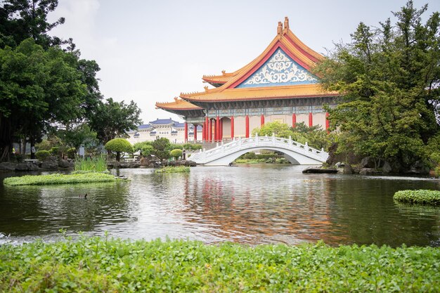 Bellissimo giardino asiatico con stagno di bonsai con ponte e maestoso tempio sullo sfondo ampio Taiwan