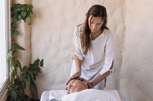 Bellissimo giovane terapista che esegue massaggi nel salone termale Trattamento di bellezza viso cura del corpo benessere