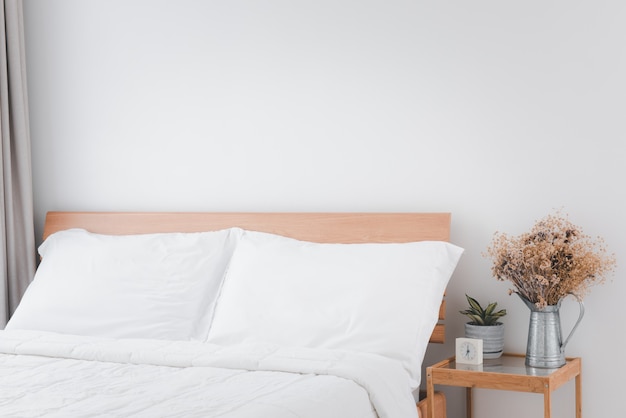 Bellissimo interno camera da letto accogliente pulito bianco con vaso di fiori verde e secco