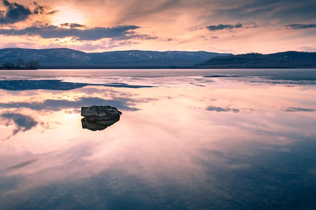 Bellissimo lago in montagna al tramonto. Ghiaccio fondente sul lago in primavera. Filtro vintage creativo