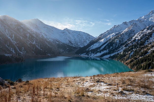 Bellissimo lago turchese circondato da montagne innevate in una giornata di sole