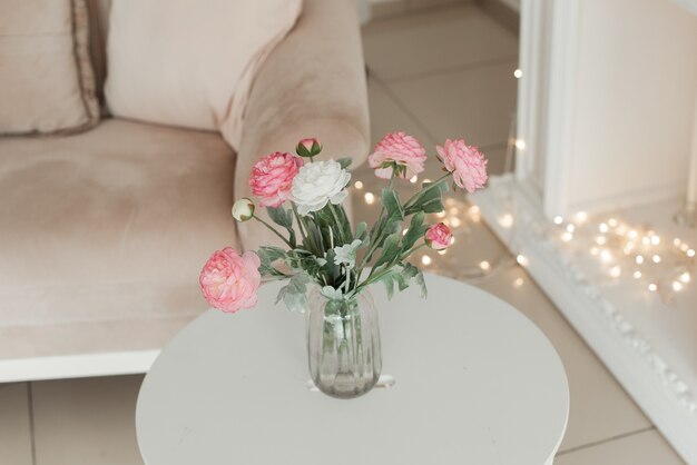 Bellissimo mazzo di fiori in un vaso di vetro su un tavolo bianco