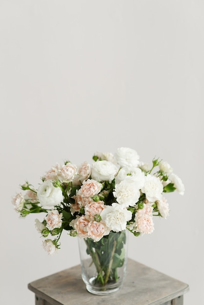 Bellissimo mazzo di fiori in un vaso su un tavolo di legno su uno sfondo bianco solido