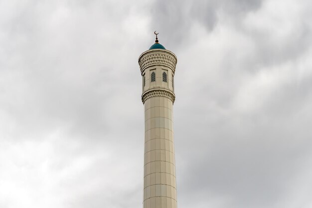 Bellissimo minareto alto in pietra bianca contro un cielo con nuvole Islam, tradizioni e religione musulmane Concetto di fede e di edifici religiosi
