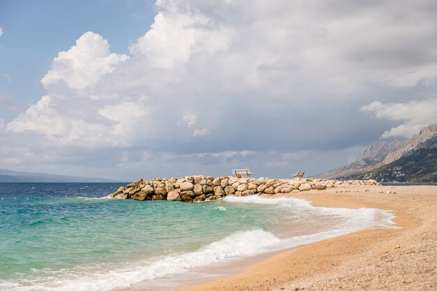 Bellissimo molo, panchine bianche e acqua di mare color smeraldo.