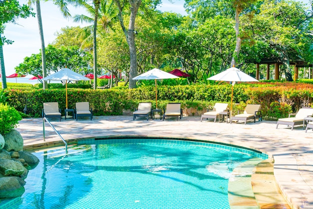Bellissimo ombrellone e sedia intorno alla piscina in hotel e resort - concetto di vacanza