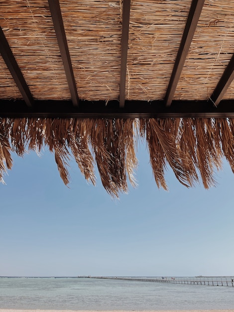 Bellissimo padiglione lounge baldacchino per rilassarsi sulla spiaggia con tenda fatta di foglie di palma secche e vista mare