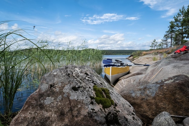 Bellissimo paesaggio Canoa parcheggiata sulla riva sabbiosa del lago con grossi sassi