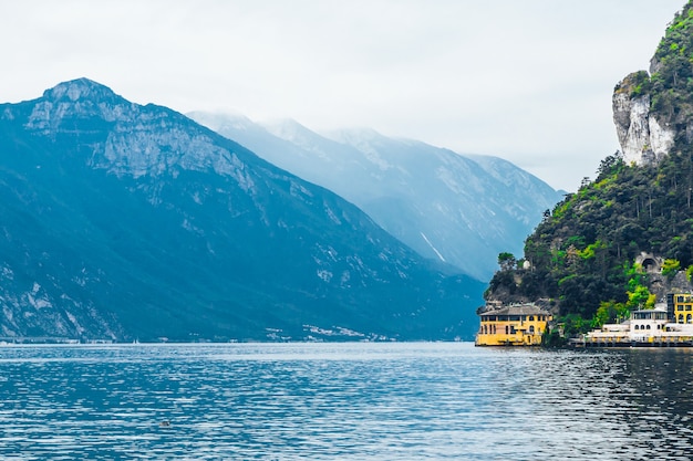 Bellissimo paesaggio con casetta gialla vicino al lago di Garda sullo sfondo delle montagne alpine.