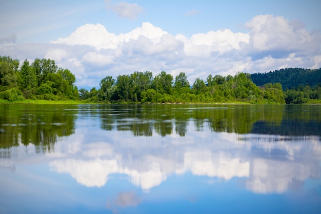 Bellissimo paesaggio con cielo azzurro e nuvole bianche riflesse nell'acqua limpida del fiume