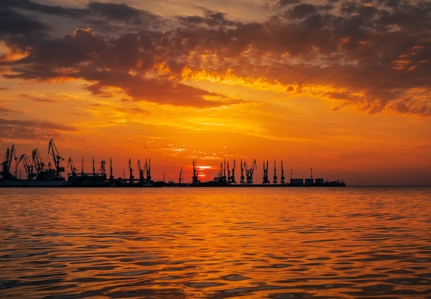 Bellissimo paesaggio con porto marittimo, cielo al tramonto infuocato e mare.