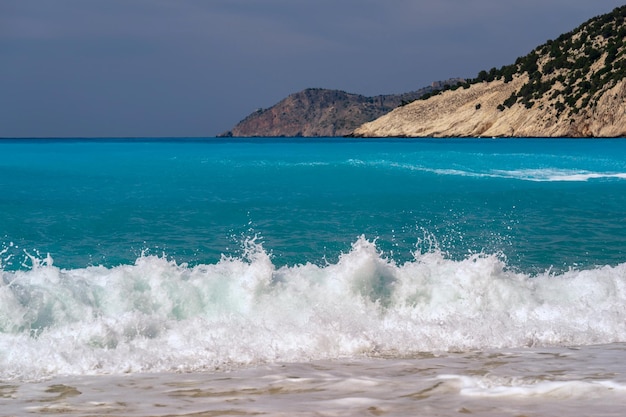 Bellissimo paesaggio di schiuma da surf e l'orizzonte del mare con colline e pendii