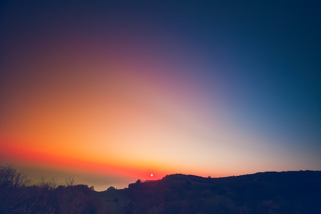 Bellissimo paesaggio estivo in montagna con il sole all'alba colorato cielo rosa arancio blu