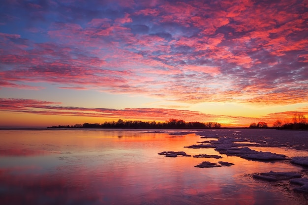 Bellissimo paesaggio invernale con cielo infuocato al tramonto e lago ghiacciato. Composizione della natura.