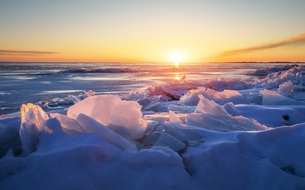 Bellissimo paesaggio invernale con cielo infuocato al tramonto e lago ghiacciato