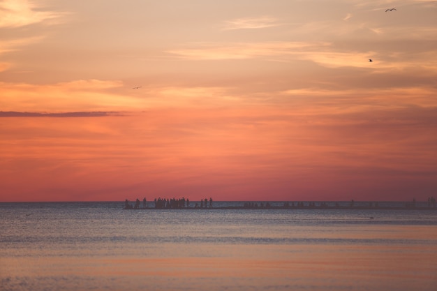 Bellissimo paesaggio marino con persone che guardano il tramonto sul mare.